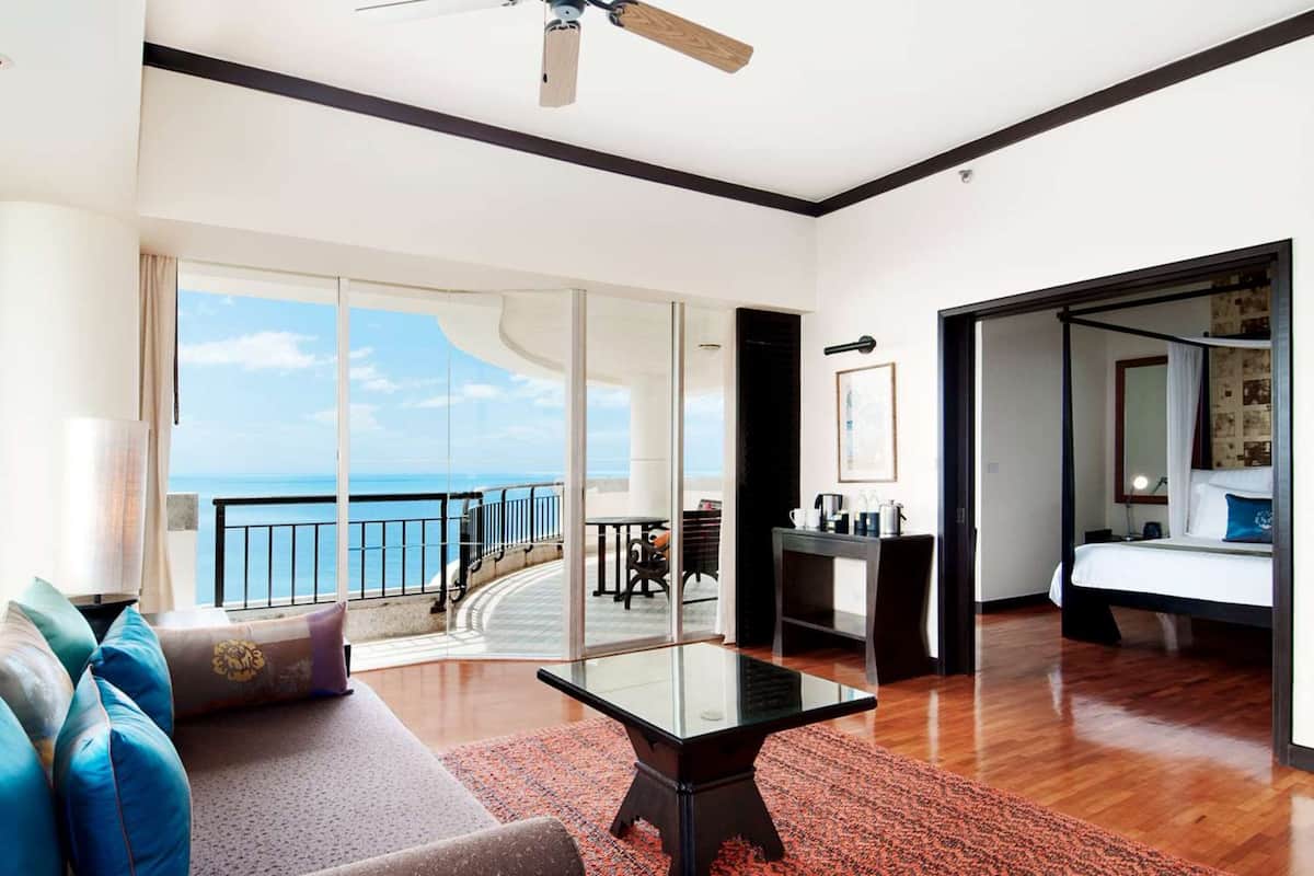 Ruime kamer met balkon en uitzicht op zee, een bed, bureau en zithoek.