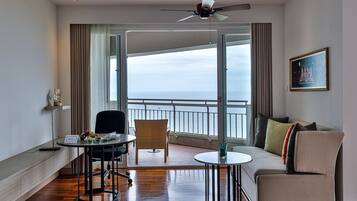 Una habitación de hotel moderna con balcón, un sofá, una mesa de comedor y una silla.