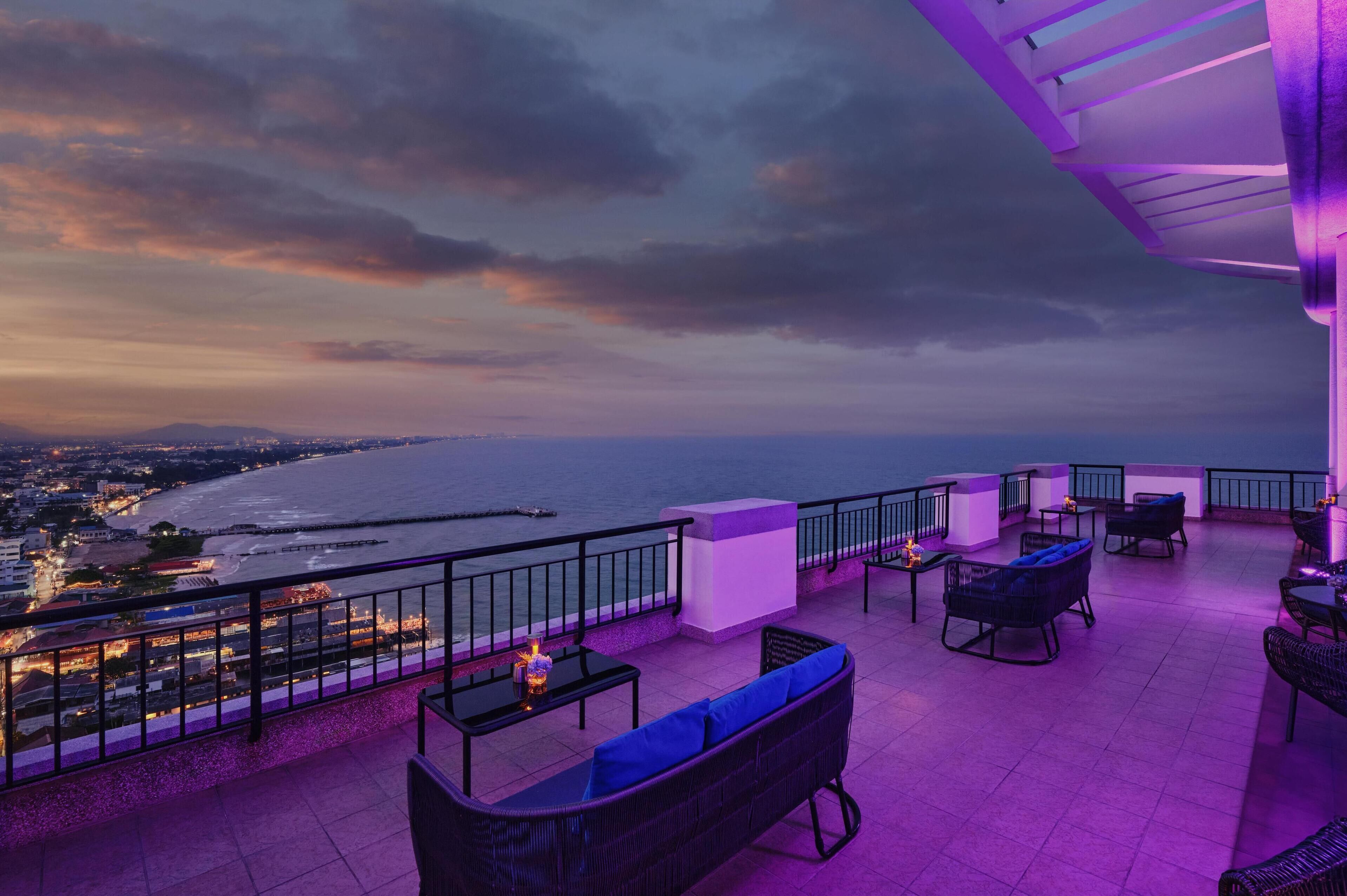Una terraza en la azotea con asientos exteriores, vistas al océano y una barandilla.