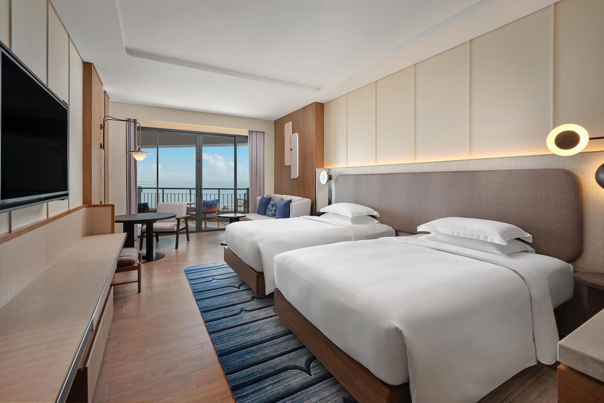 Een hotelkamer met twee bedden, een televisie, een bureau en uitzicht op de lucht.