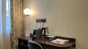 A hotel room with a desk, a lamp, a coffee machine, and a sign indicating the room type.