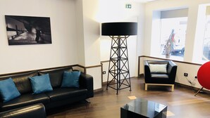 Una sala de estar moderna con un sofá de cuero negro, una mesa de centro de vidrio y una lámpara de pie.