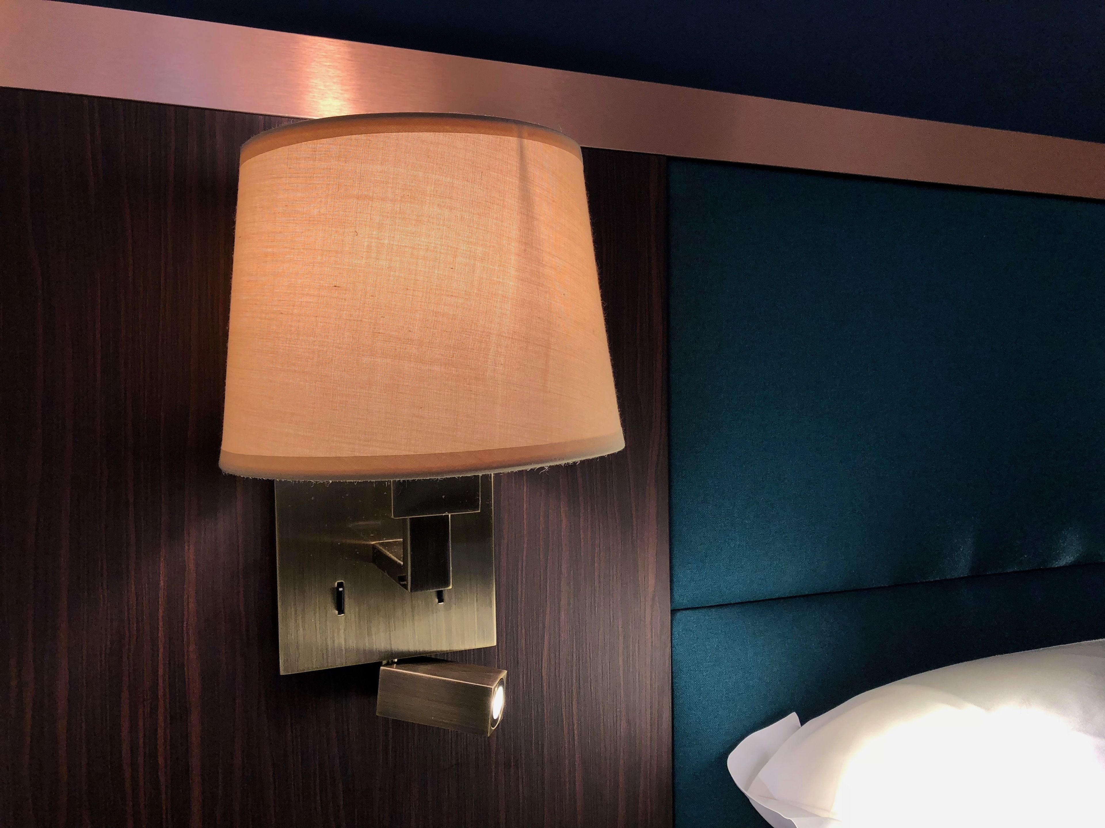 Une lampe murale dotée d’un abat-jour en tissu, d’un interrupteur métallique et d’une fente en forme de trou de serrure.