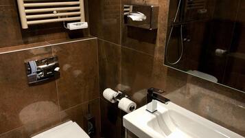 Une salle de bain moderne avec un lavabo, des toilettes et un bidet, tous de couleur blanche. On y trouve également un porte-serviettes, un miroir et une cabine de douche en verre.