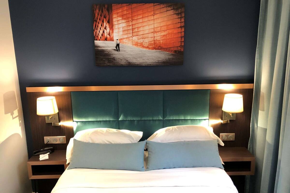Een hotelkamer met een bed, twee nachtkastjes, een hoofdeinde en een aan de muur hangend schilderij.