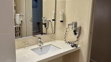 A bathroom with a white sink, a mirror, a towel rack, and a trash can.
