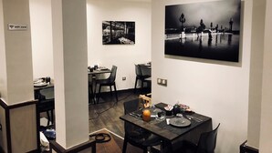 Un comedor con una mesa preparada para dos, una fotografía blanco y negro en la pared y un cartel de zona WiFi.