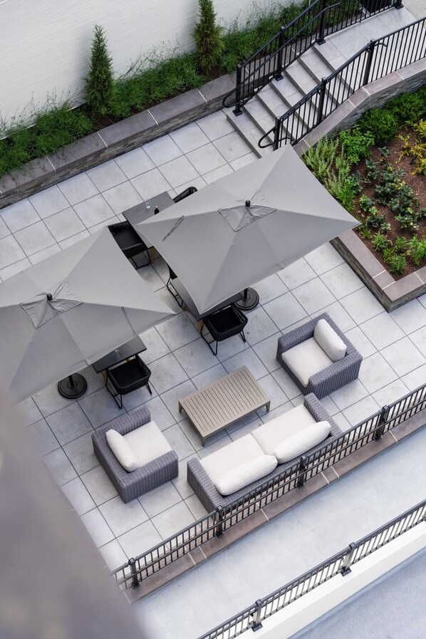 Una terraza en la azotea con mobiliario exterior, incluyendo sofás y una mesa, y una escalera que sube a un nivel superior.