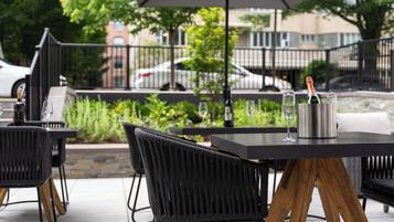 An outdoor patio with a table, chairs, and a bottle of champagne.