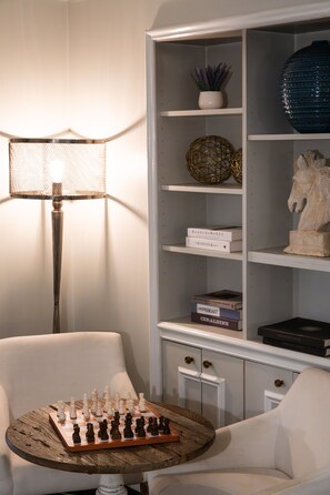 Relax and engage in leisure activities in this inviting space, featuring a chess set, comfortable seating, and a warm ambiance.