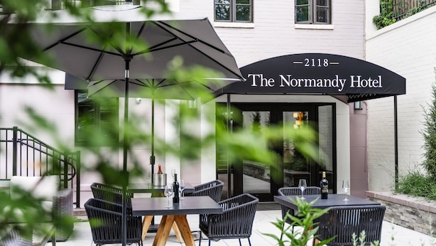 Normandie-hotellets uteservering med bord, stolar och parasoller.