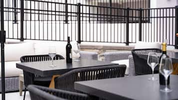An outdoor seating area with black wicker furniture, wine glasses, and bottles.