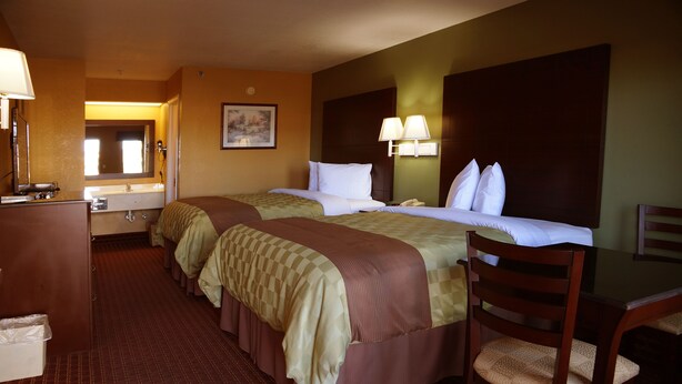 A hotel room with two beds, a desk, a chair, a desk lamp, a telephone, and a mirror. - Executive Inn Opp (Opp)