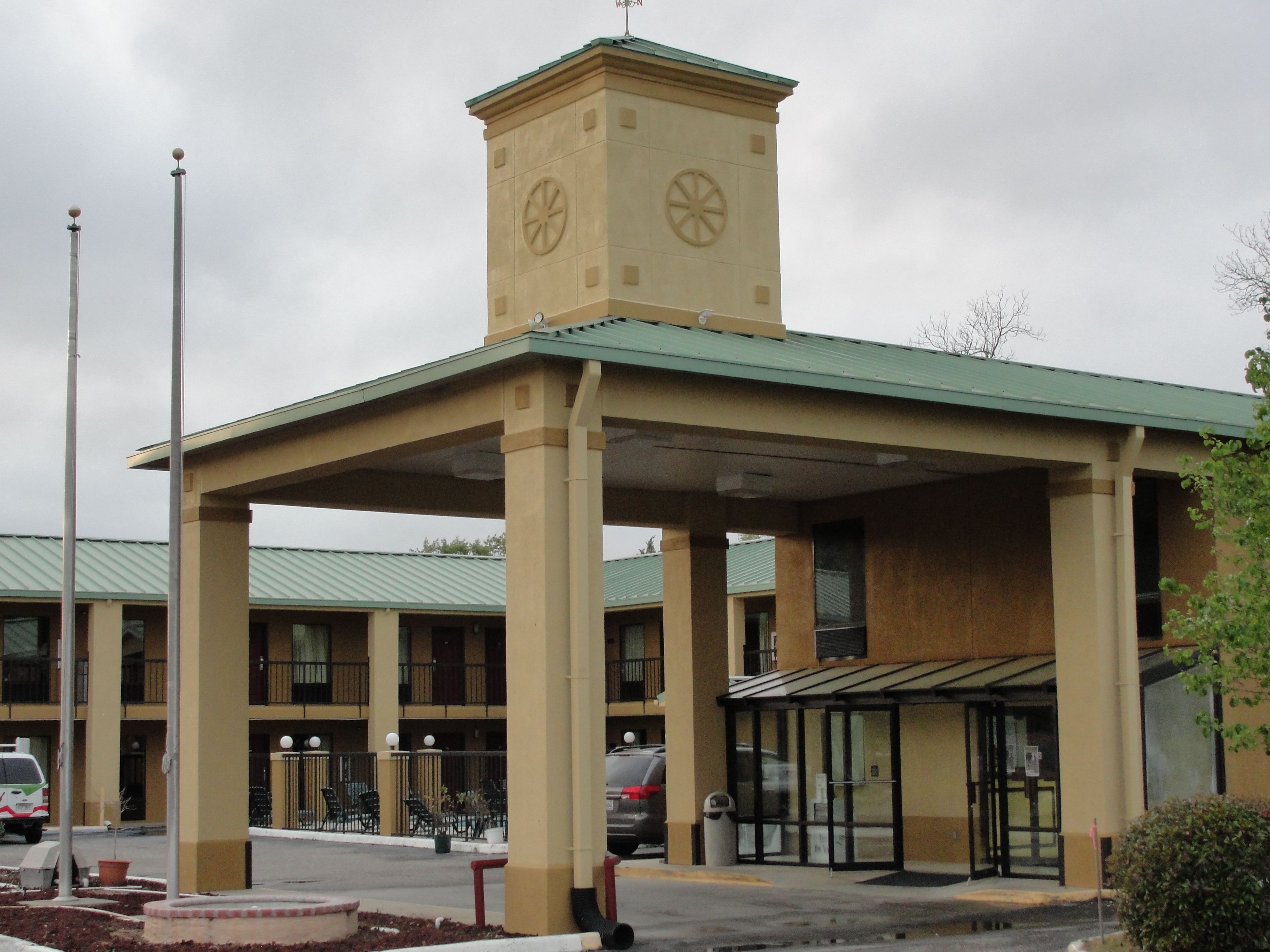 A hotel with a central tower, covered outdoor seating area, and a parking lot.