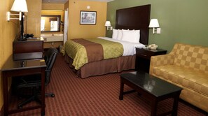 A hotel room with a bed, desk, chair, and sofa.