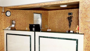 A reception desk with a clock, a computer, and a decorative peacock statue. - Executive Inn Opp (Opp)