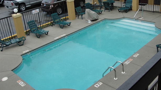 A pool area with lounge chairs and a sign indicating a 5 ft depth. - Executive Inn Opp (Opp)