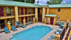 A motel with a pool, multiple balconies, and a sign indicating pool rules. - Executive Inn Opp (Opp)