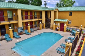 A motel with a pool, multiple balconies, and a sign indicating pool rules.