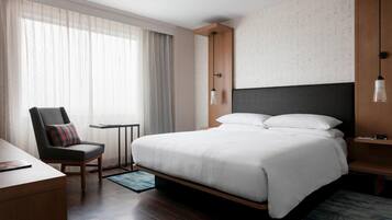 Habitació d'hotel moderna amb un llit gran, un escriptori, una cadira i una taula petita.
