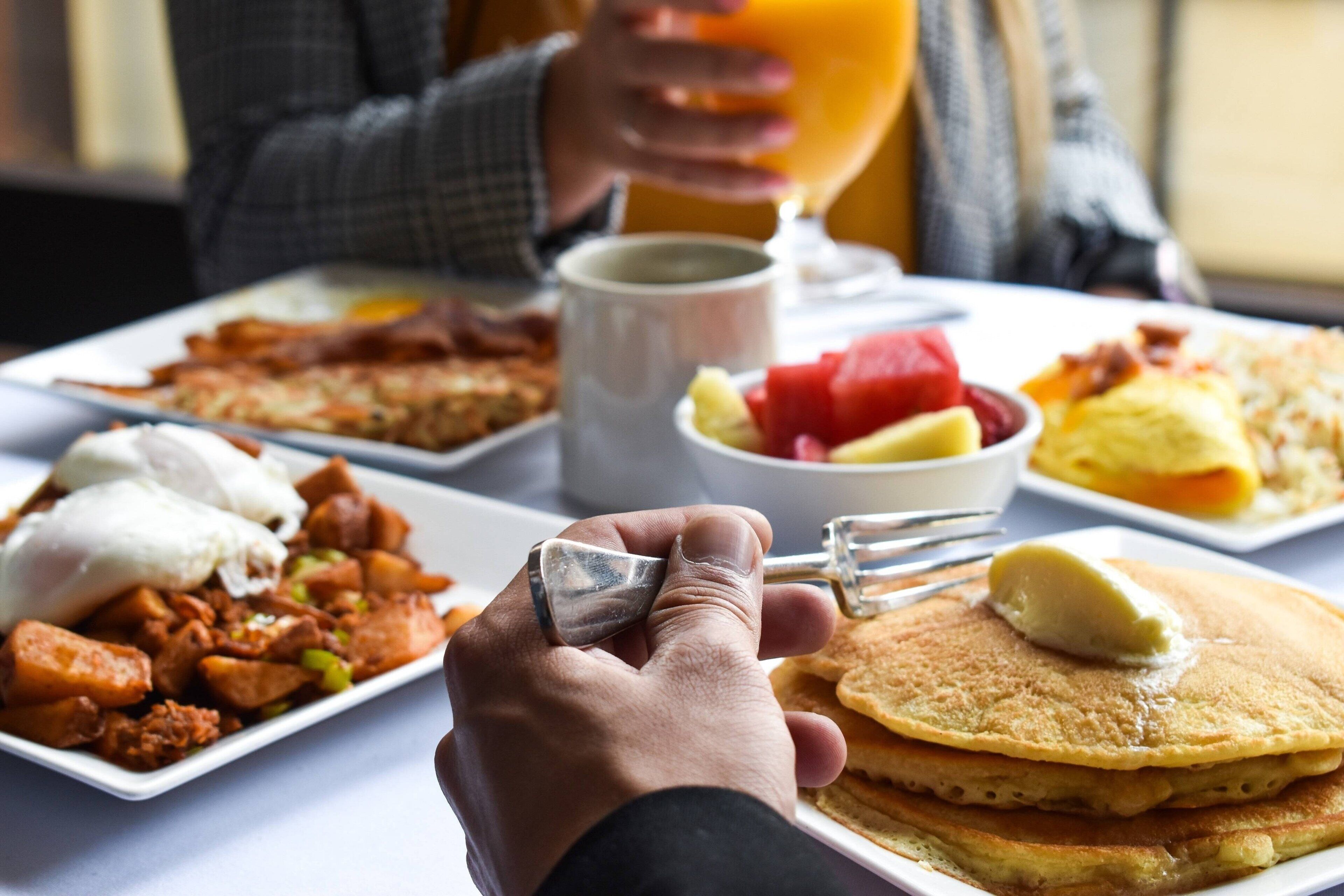 A breakfast setting with pancakes, eggs, and various side dishes.