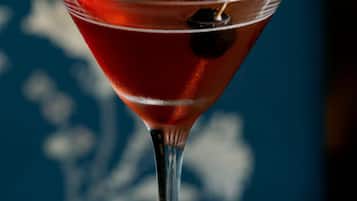A martini glass with a cherry on a coaster.