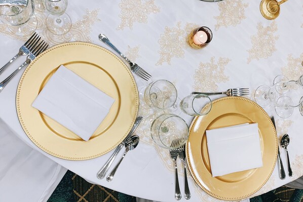 Una mesa servida con platos de borde dorado, cubiertos y copas de vidrio.