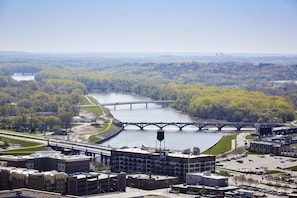 Panoramic city view with a river, lush greenery, and a mix of modern and historic buildings.