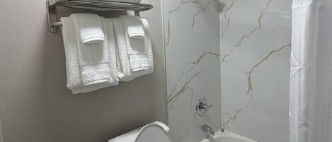 Une salle de bain équipée de toilettes, d’une baignoire et d’un porte-serviettes avec des serviettes pliées.