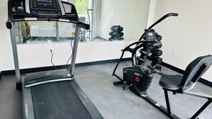 A gym with a treadmill, an elliptical, and a stationary bike.