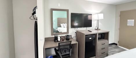 Una habitación de hotel con escritorio, silla, televisor y cama.