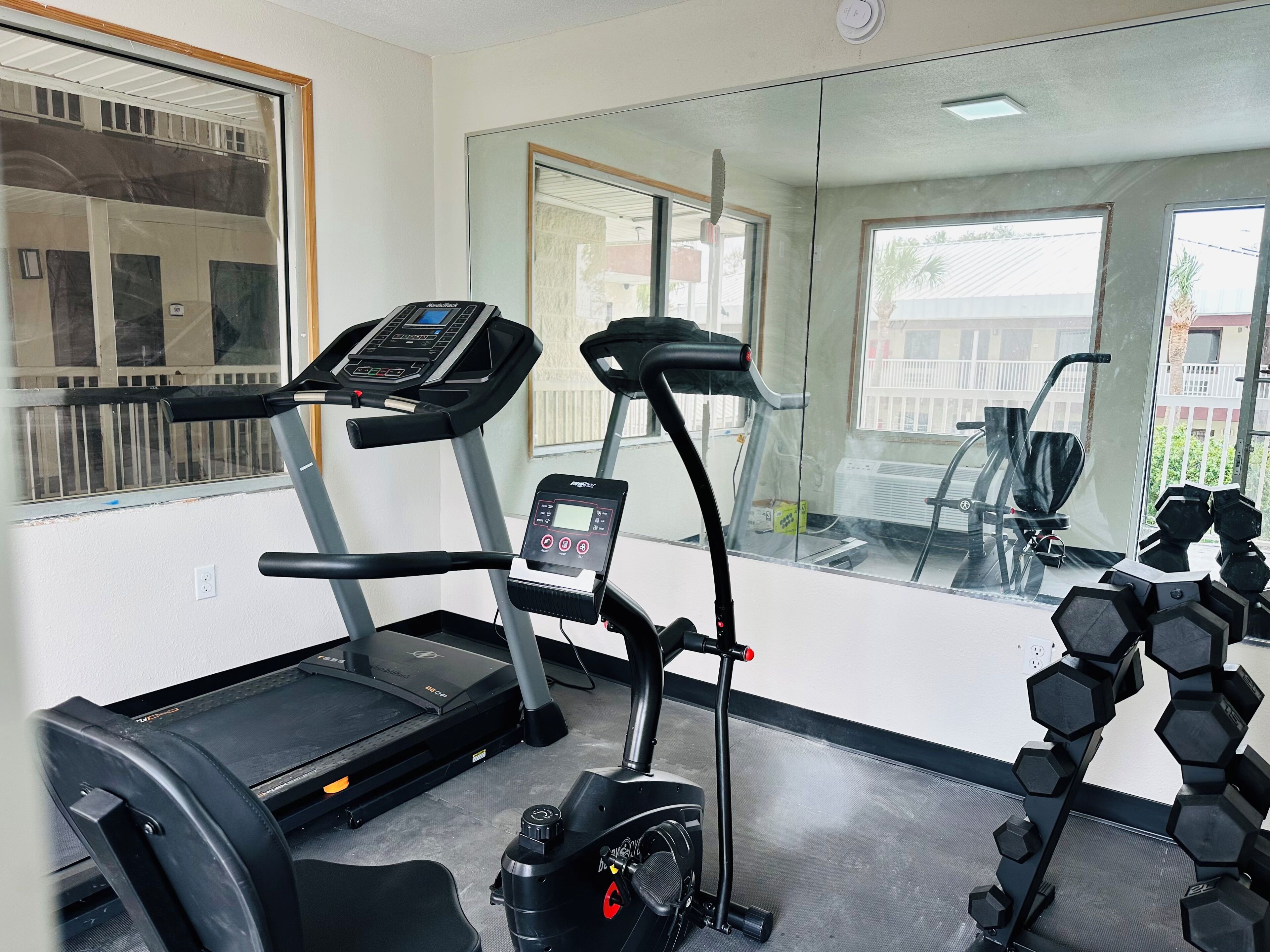 A gym with treadmills, an elliptical, and a set of dumbbells.