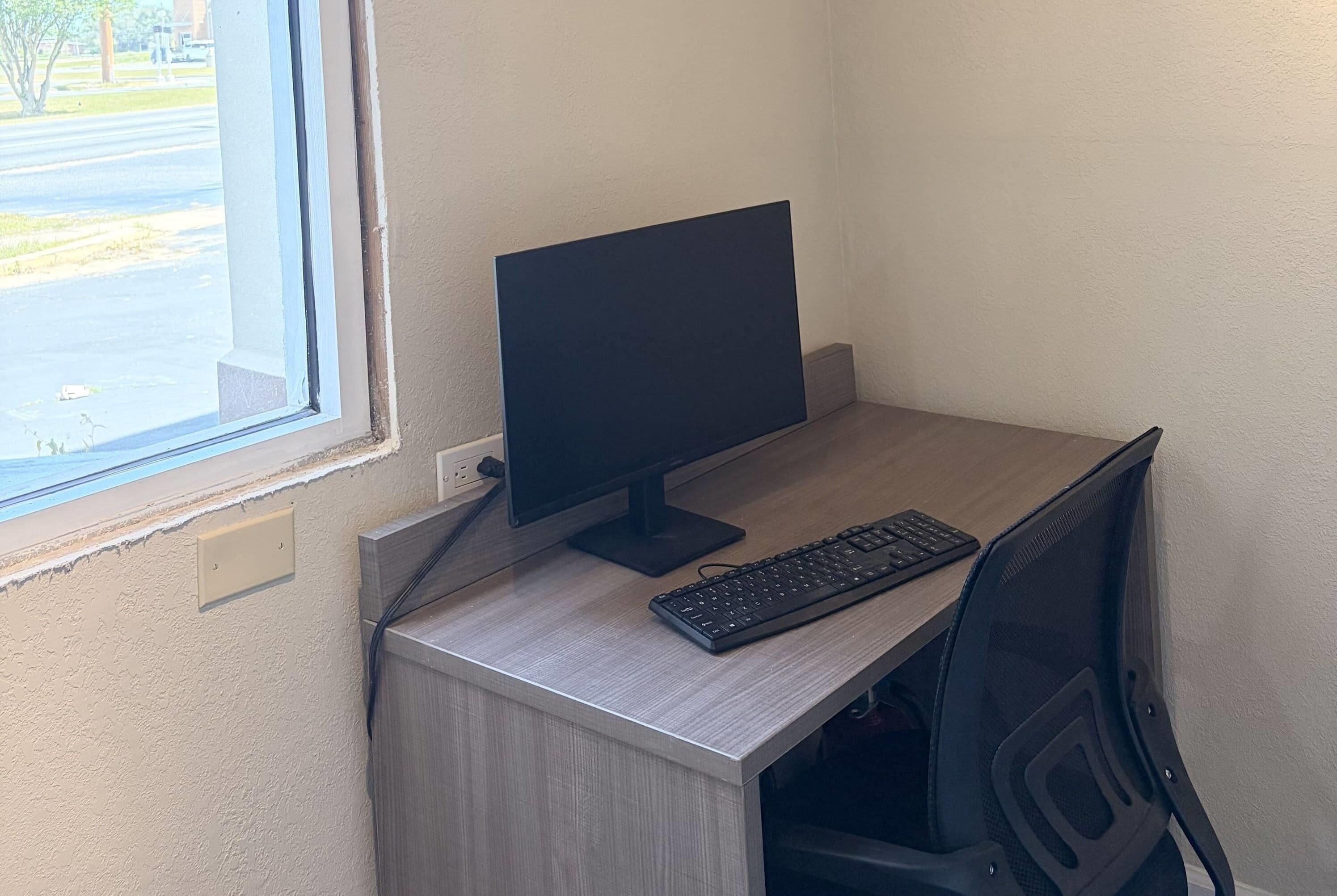Un escritorio con monitor, teclado y silla.