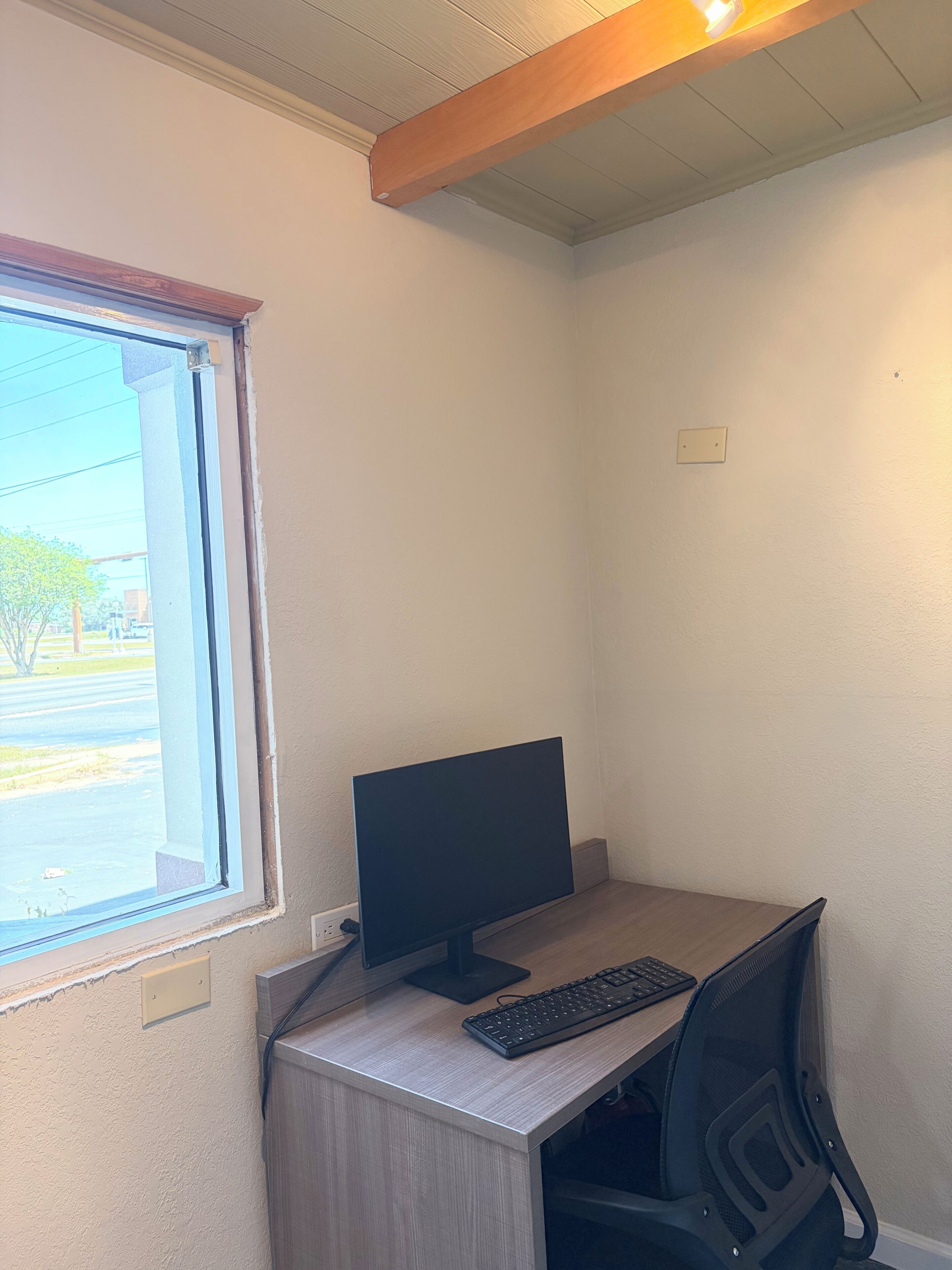 Una oficina en esquina con escritorio, computadora y silla.