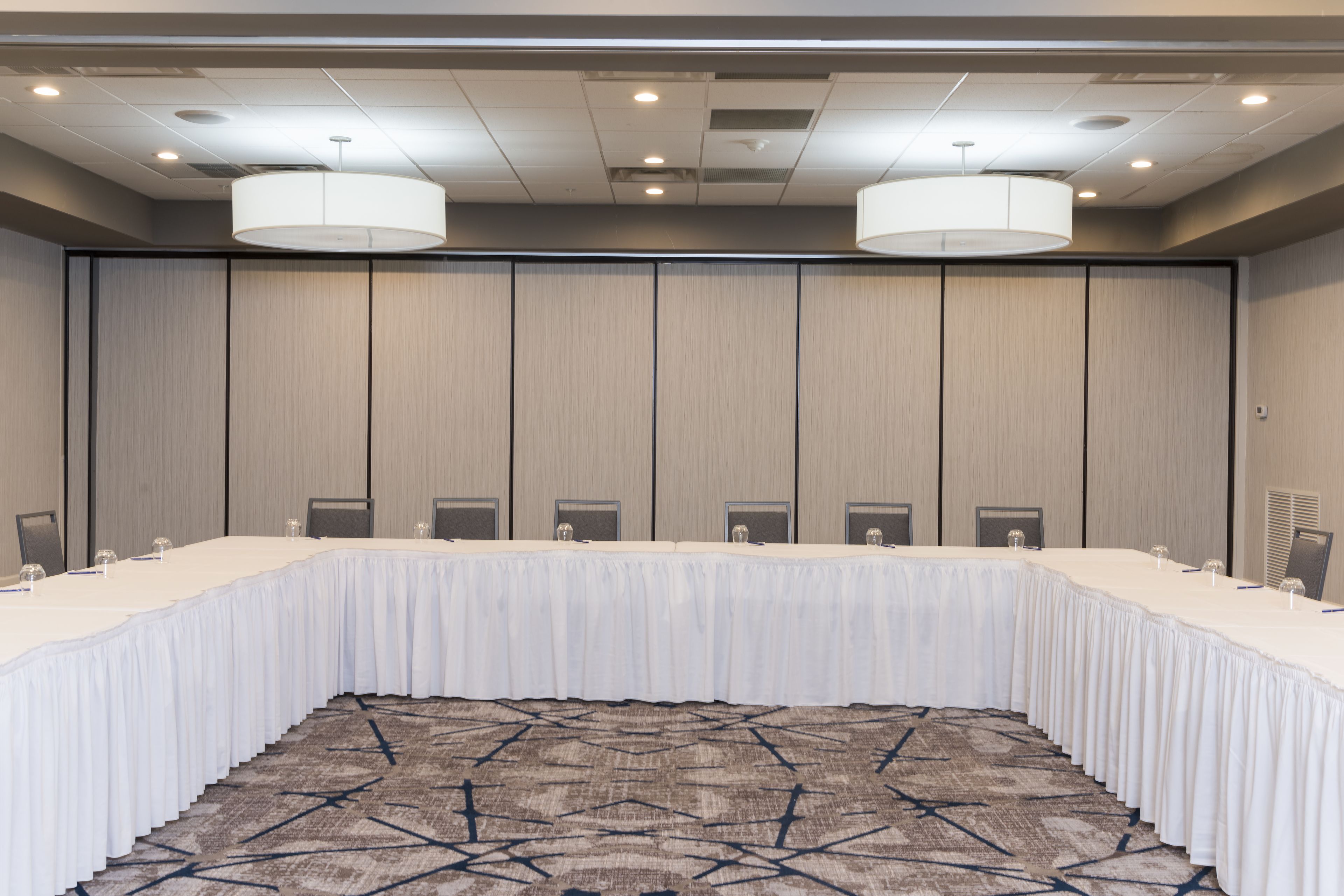 Una sala de conferencias con una larga mesa, sillas y una alfombra estampada.