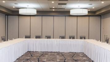 A conference room with a long table, chairs, and a patterned carpet.