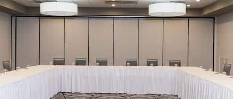Una sala de conferencias con una larga mesa, sillas y una alfombra estampada.