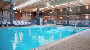 An indoor swimming pool with clear lane markings, lounge chairs, and a mezzanine level with tables and chairs. - The Center Hotel Grand Rapids Airport (Grand Rapids)