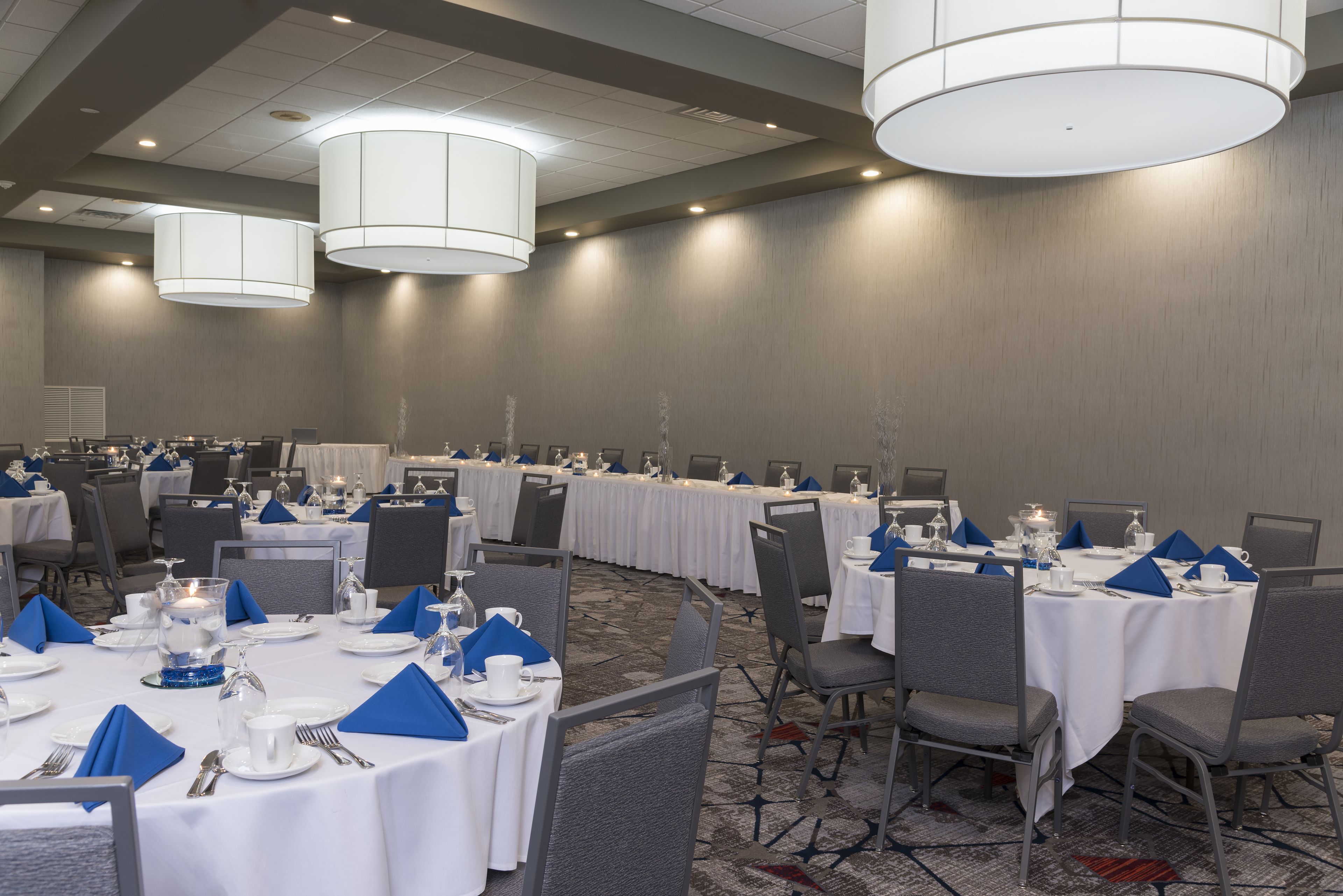 A conference room with round tables, chairs, and white tablecloths.