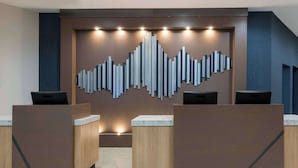 A reception area with a modern design, featuring a central wall with a geometric light installation and two reception desks. - The Center Hotel Grand Rapids Airport (Grand Rapids)