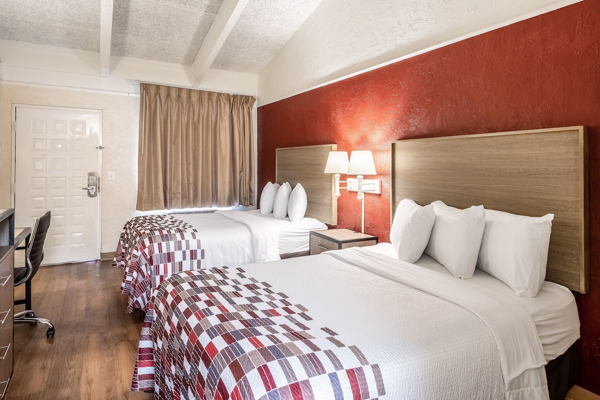 Une chambre d’hôtel avec deux lits, un bureau et une chaise.