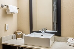 Une salle de bain avec un lavabo blanc, un miroir, un porte-serviettes et des toilettes.
