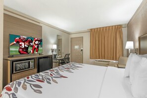 A hotel room with a bed, a television, a desk, and a chair.