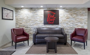 Hall de um Red Roof Inn com parede de pedra, móveis de couro e uma mesa de centro.