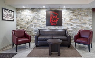 Hall del Red Roof Inn con parete in pietra, arredi in pelle e tavolino da caffè.