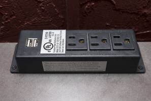 Une prise électrique noire, dotée d’une étiquette et d’un port USB.
