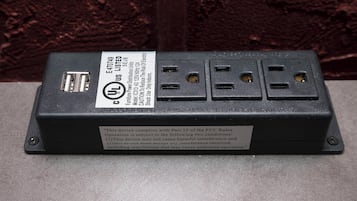 A black electrical power strip with multiple outlets and a USB port, labeled with UL certification and FCC compliance information.