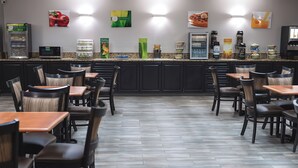 Un restaurant amb una barra que mostra diferents plats i una zona de seients amb taules i cadires.