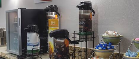 Ein Buffet mit Kaffeeautomaten, einem Wasserkühler und Schalen mit Snacks.