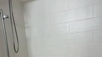 A bathroom with a white bathtub, a shower, and two grab bars on the wall.